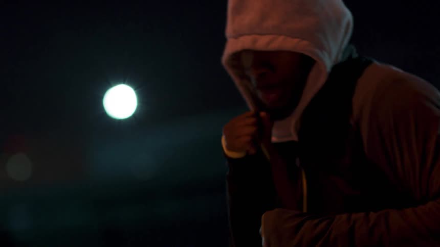 A man shadow boxes outside at night