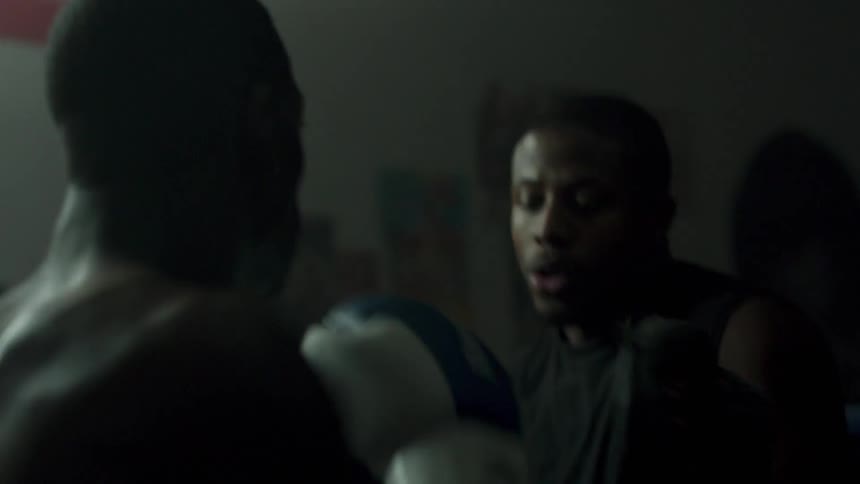 A boxer is training with a coach in a boxing ring