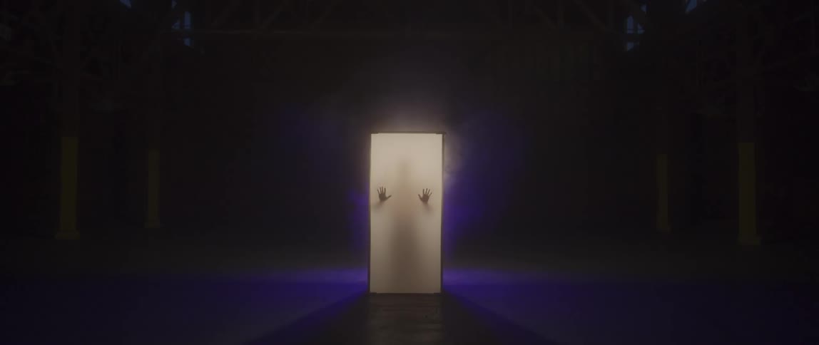 A silhouetted man presses his hands against a glowing wall