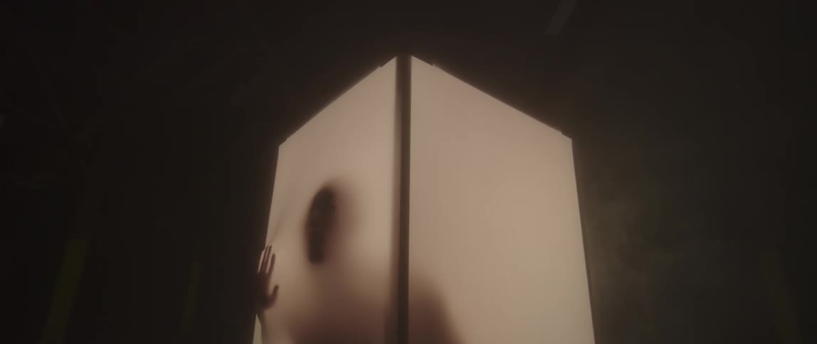 A silhouetted man stands in an illuminated enclosure