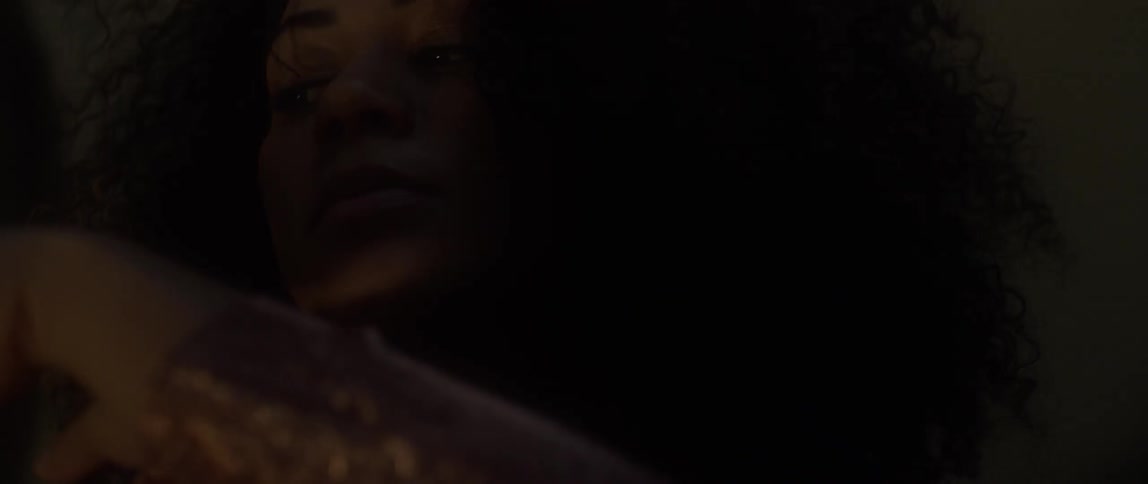 A woman sits in a dark room with flashing dim lights