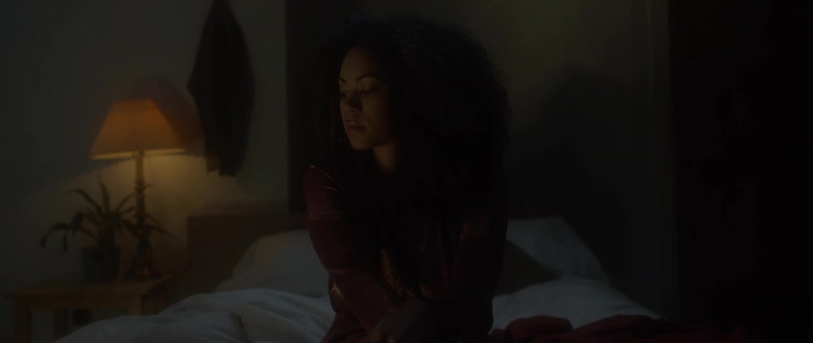 Person sitting on a bed in a dimly lit room