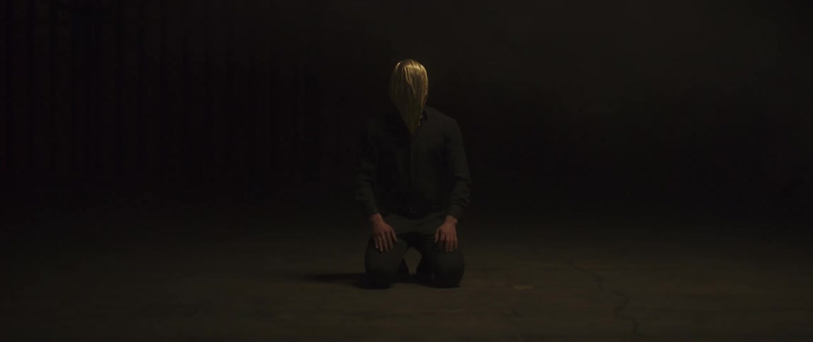 A man in a hood kneels down