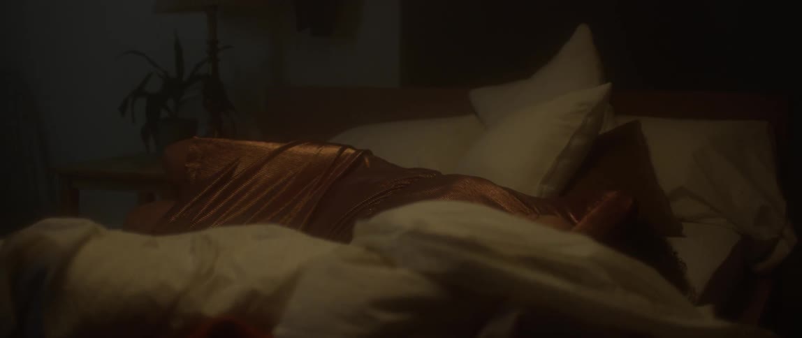 Woman lies down on a bed with pillows and blankets
