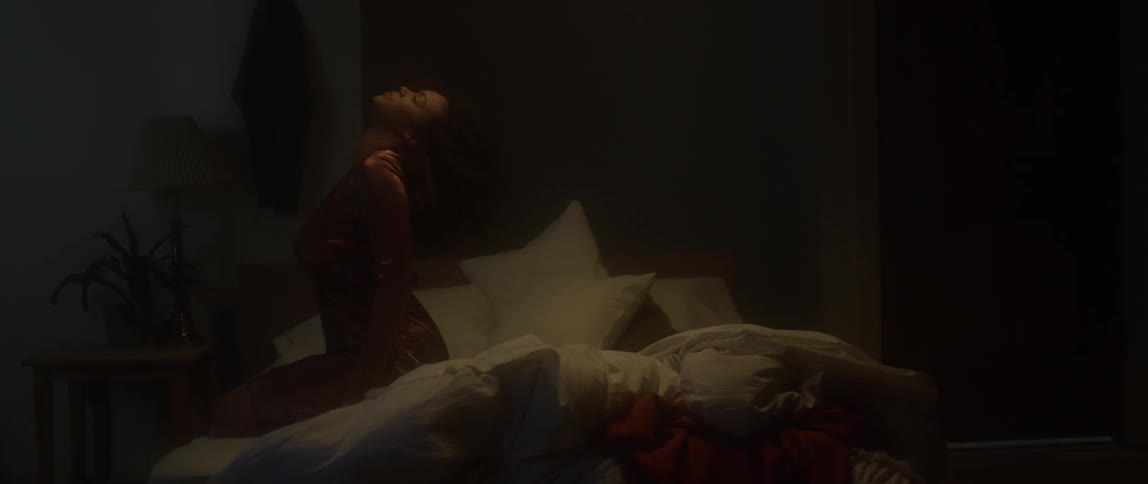 A woman sits and leans back on a bed