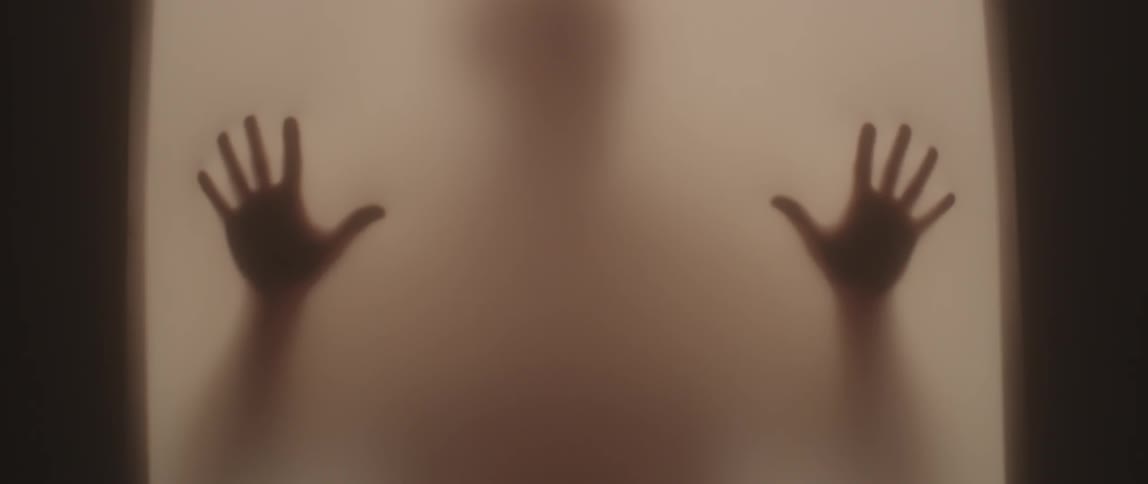 A man inside a box is rubbing against the translucent walls