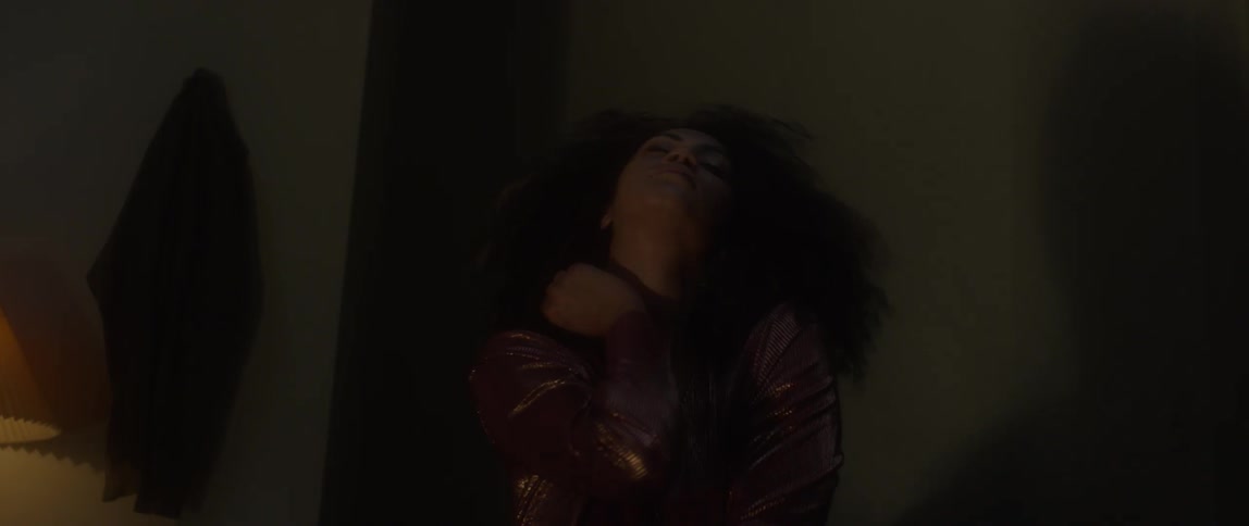 Woman rubs her neck in a dark room