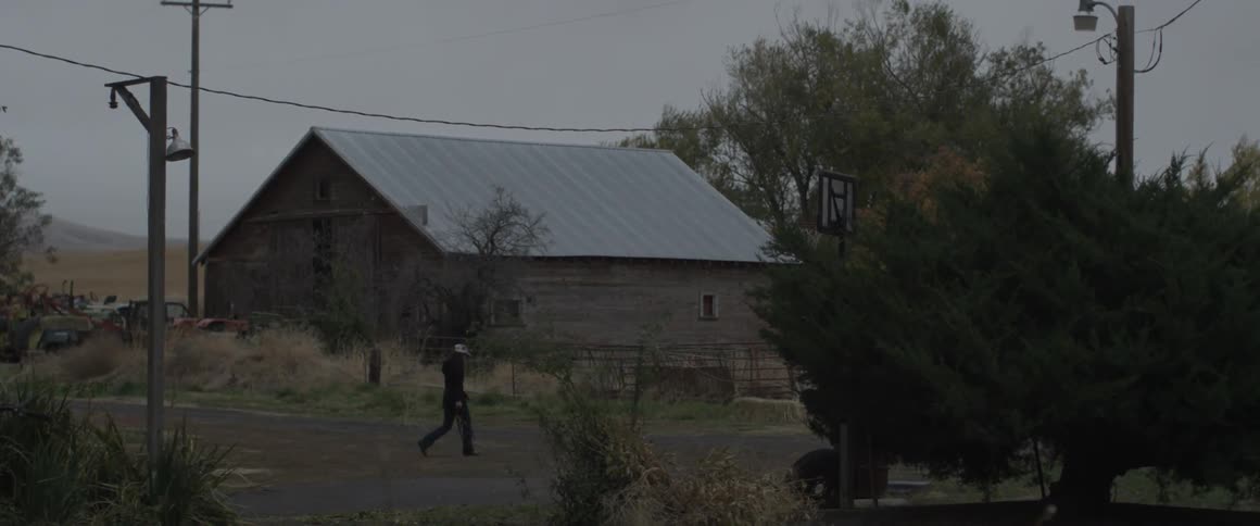Person on a farm walks towards a corral
