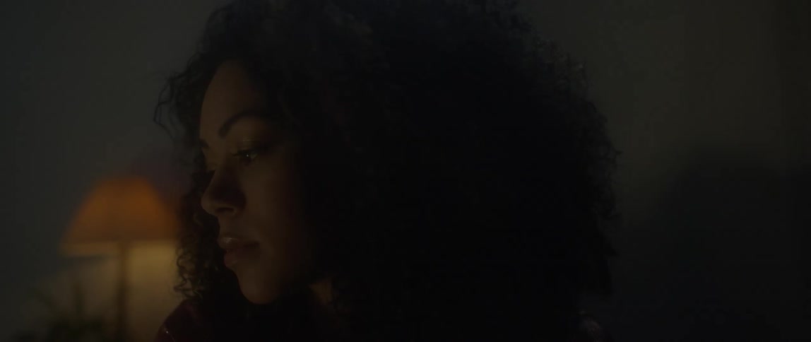 Woman with dark curly hair blinks her eyes