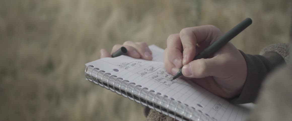 Person writes in a spiral bound notebook