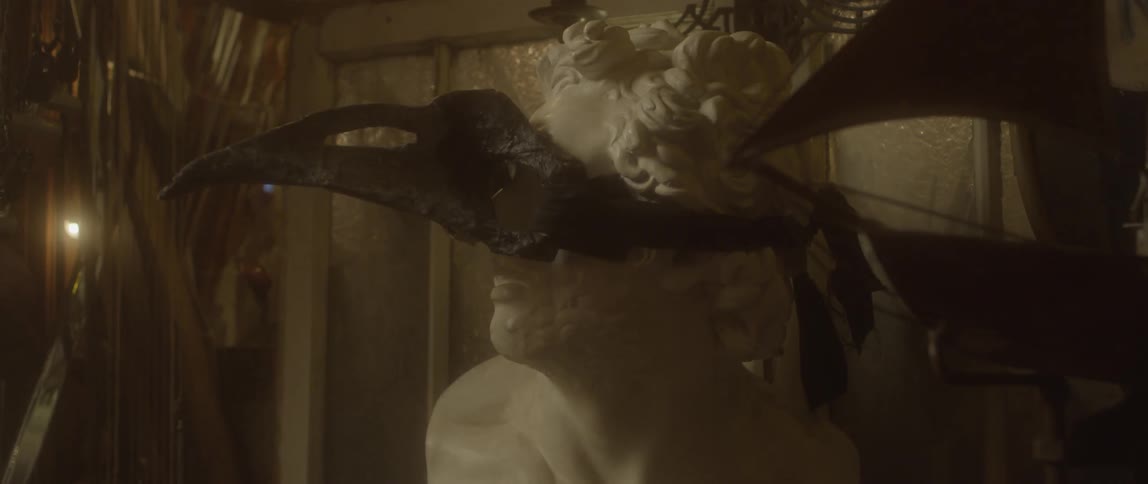 A mask sits on a white statue