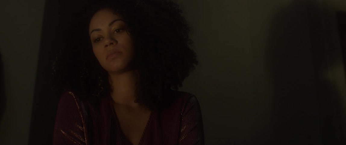 A woman stares blankly in a dark room
