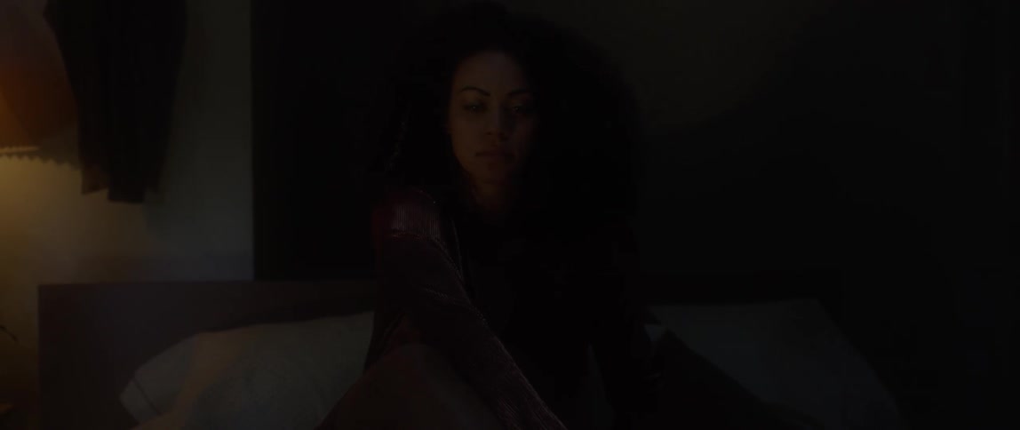 A woman is sitting in her bed in the dark