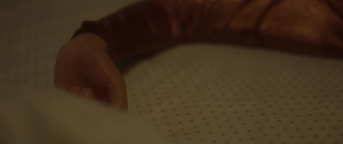 Woman with a ring on her finger moves her arm over a sheet