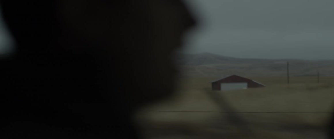 A man rides in a vehicle while traveling through a rural area
