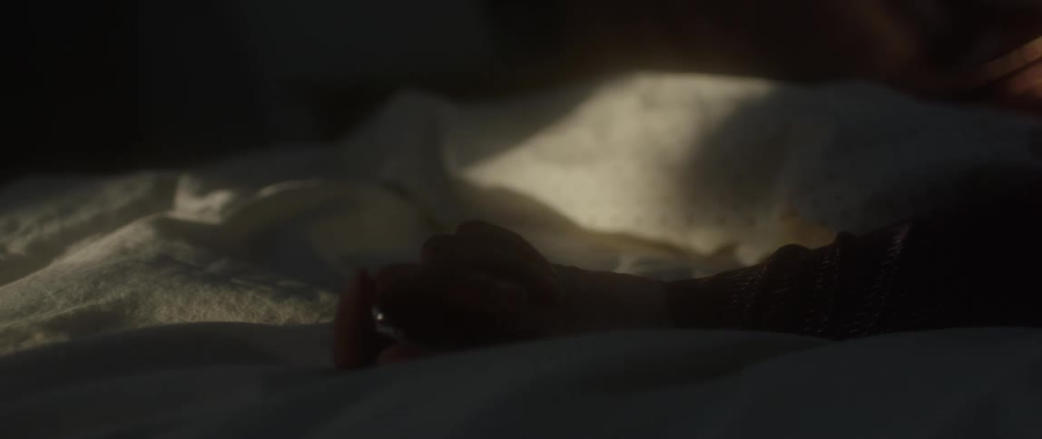 A woman rubs her hand on a blanket in bed