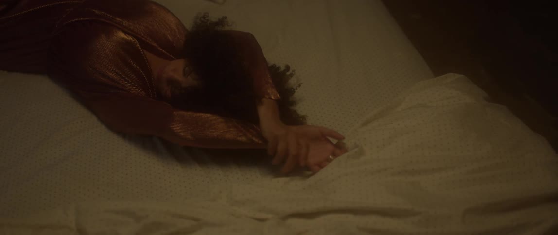 A woman stretches her arms while laying in bed