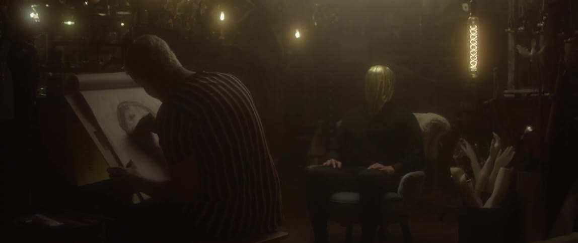 Artist sketches person in a low lit room