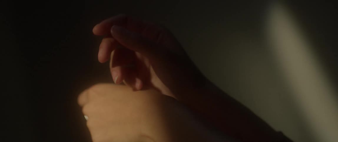 A woman moves her hands in sunlight and shadow