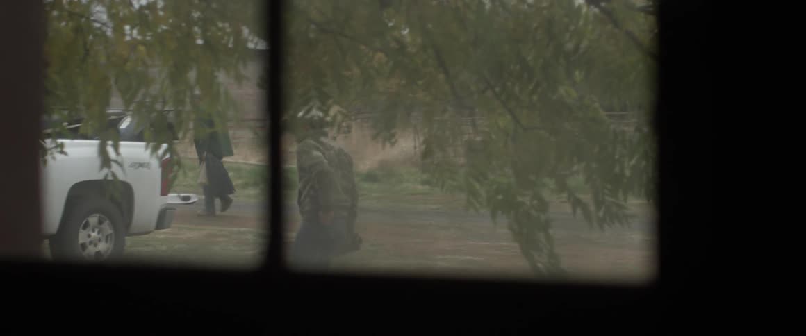 View looking out a window at men walking towards a white truck