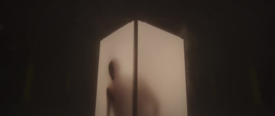 A man presses his face and hand against a box he is in