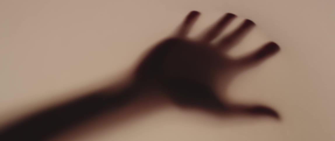 A silhouetted hand is pressed against a fabric wall