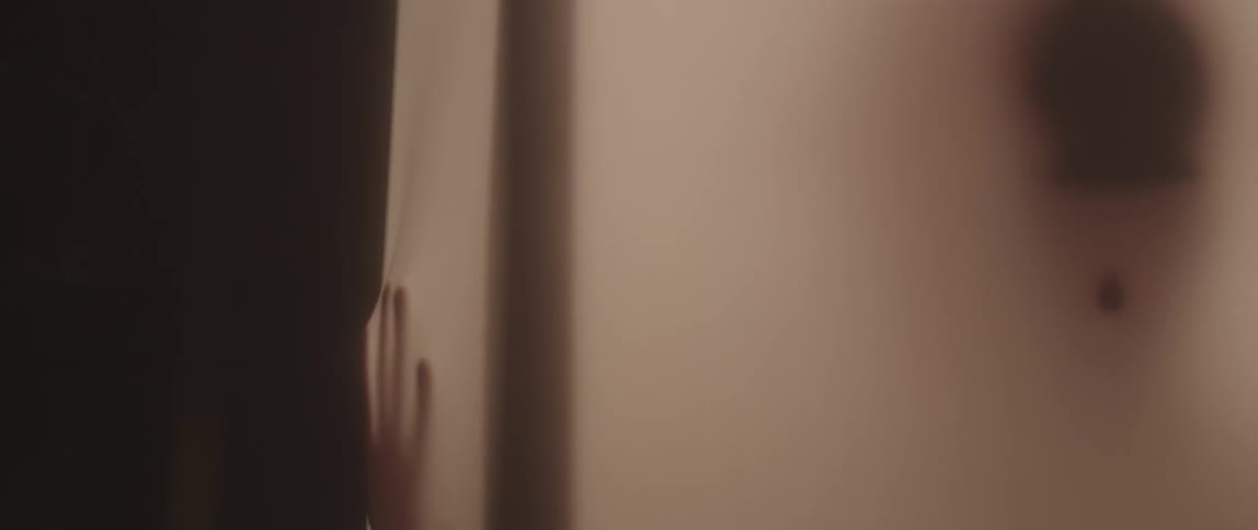 A person in a small lit room is rubbing the walls