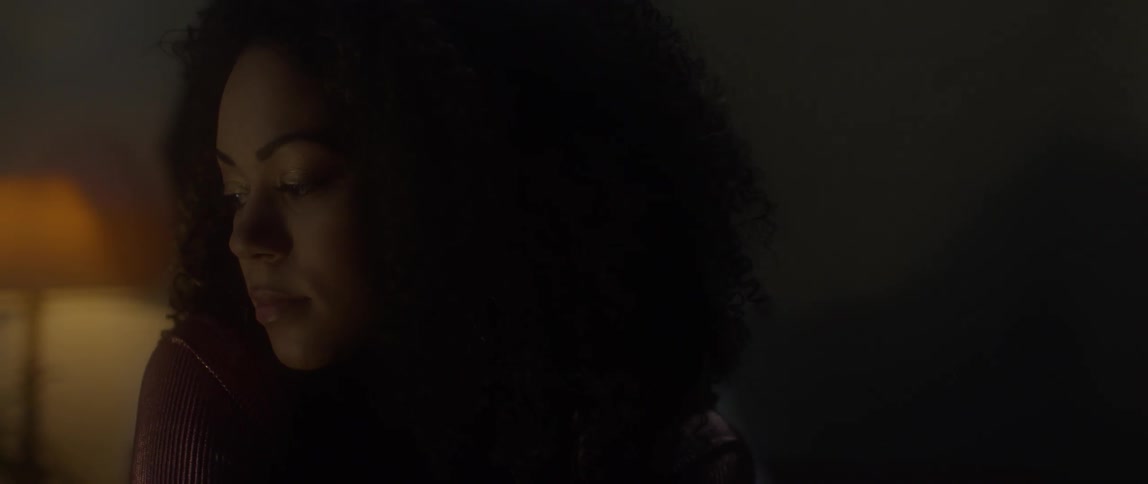 A woman looks around a dark bedroom