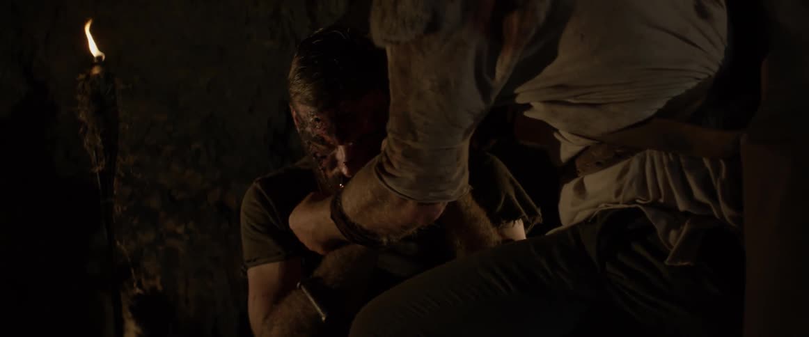 A man places a necklace over an injured man's head