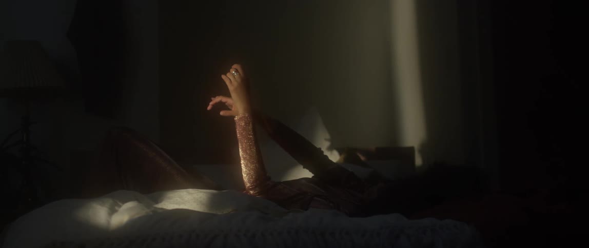 A woman lays in bed with her arms lifted into the air