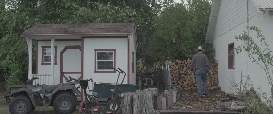 A man takes corded wood from a cart and places it in a pile