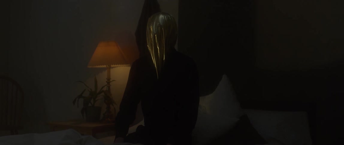A woman sits in a dark bedroom