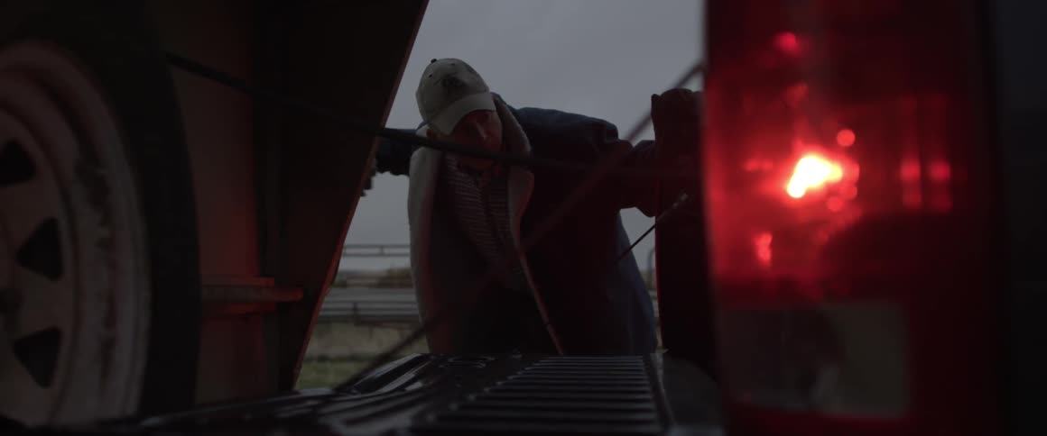 Man wearing a hat turns a large crank