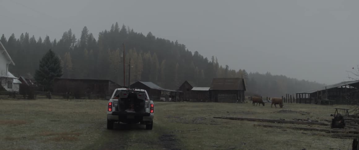 A truck carrying an atv approaches a farm