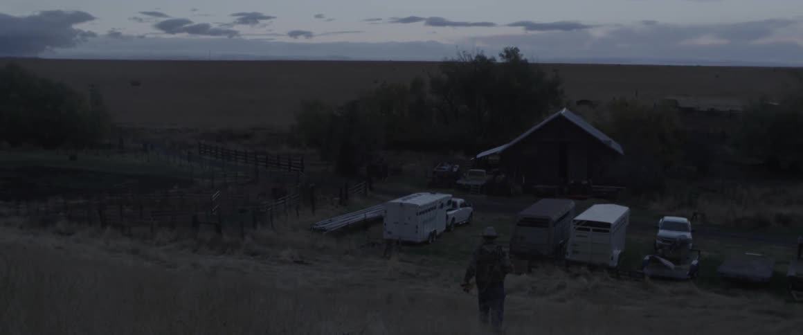 A man walks down a hill towards trailers and trucks