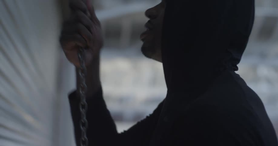 Man wearing a hooded sweatshirt pulls on a chain