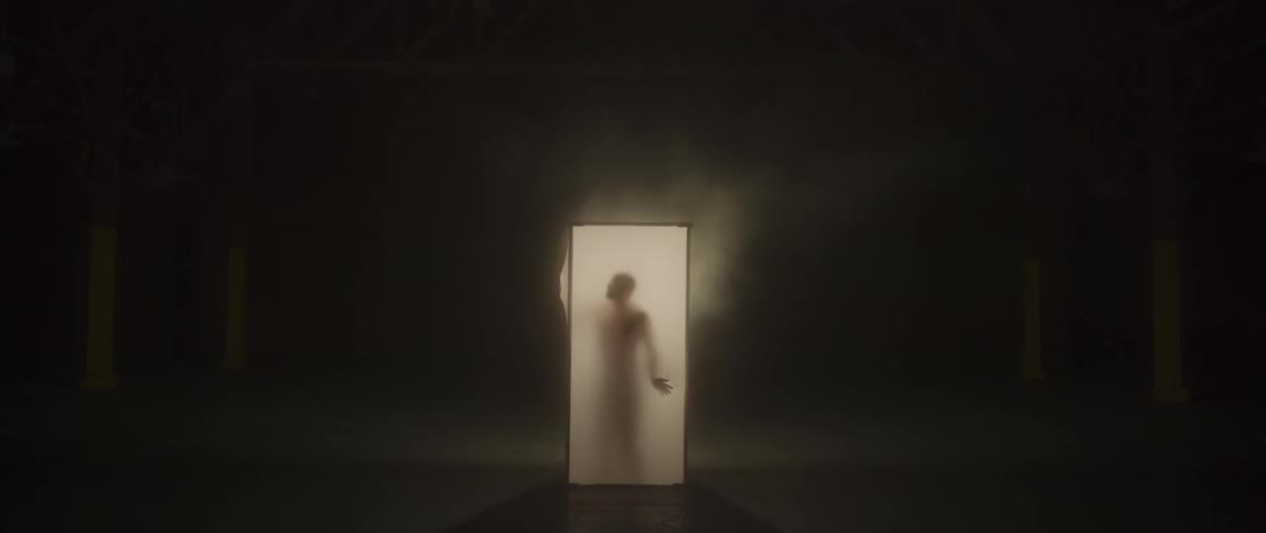 A man stands up inside of a small lit box