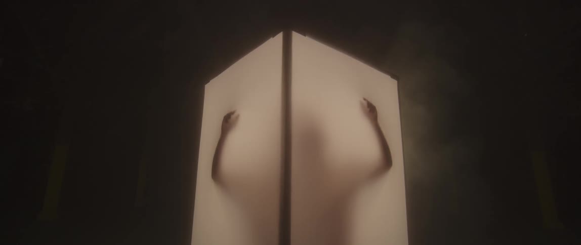 A person in a small box rubs his hands along the walls