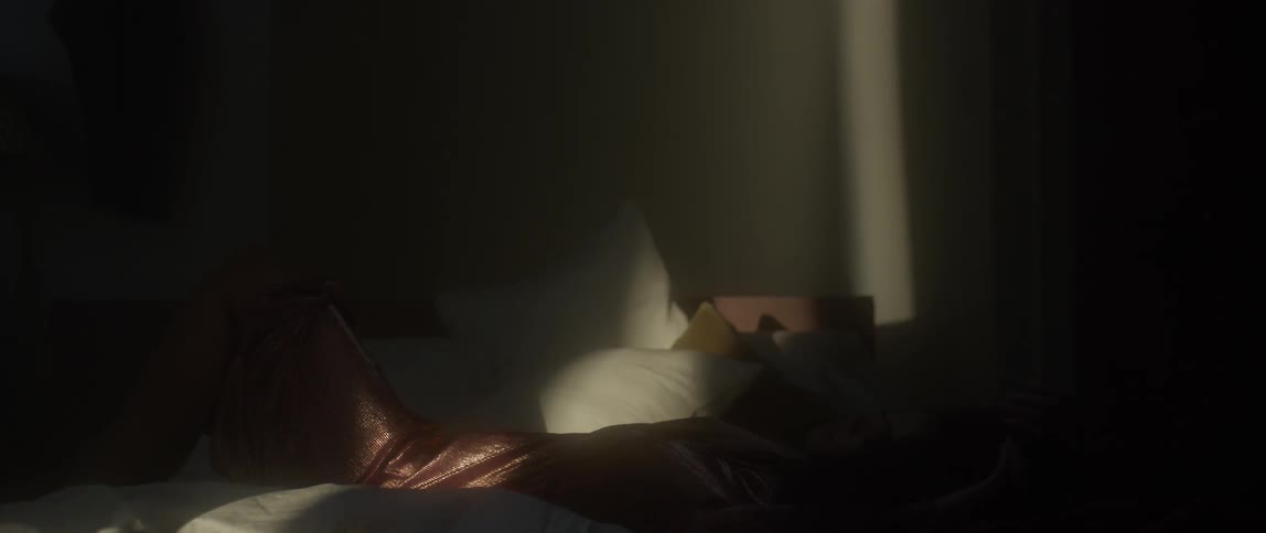 A woman lies back on a bed stretching her arms over her head