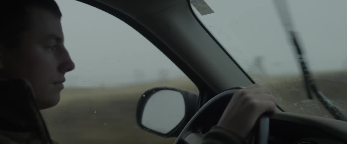 A man drives a car while its raining