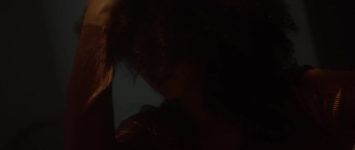 Woman moves head and arms around in dim light
