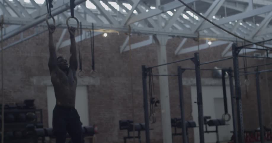 A man pulls up a weight ball with his legs hanging from hooks