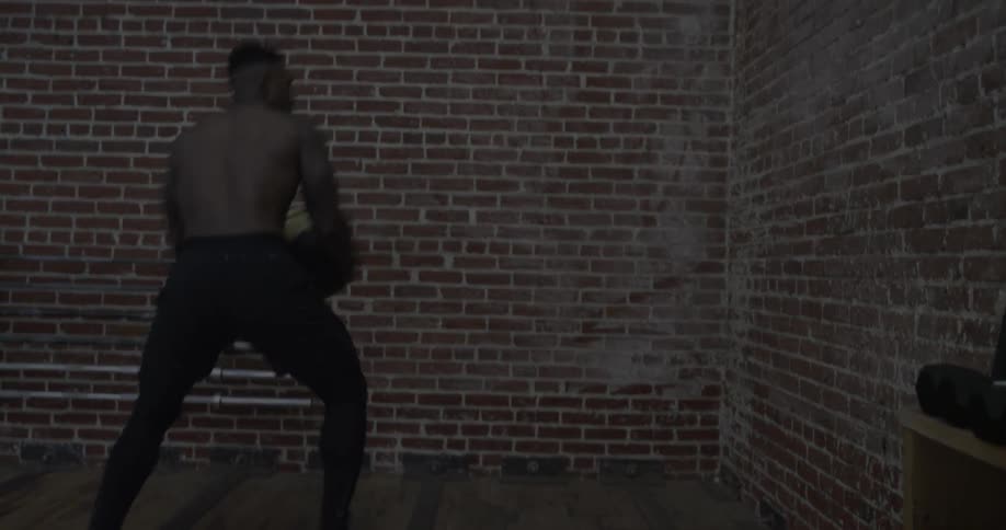 A man bounces an exercise ball off a brick wall and catches it repeatedly
