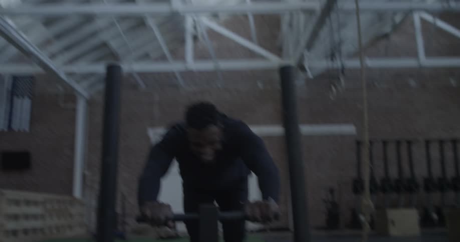 A man pushes a sled in a gym