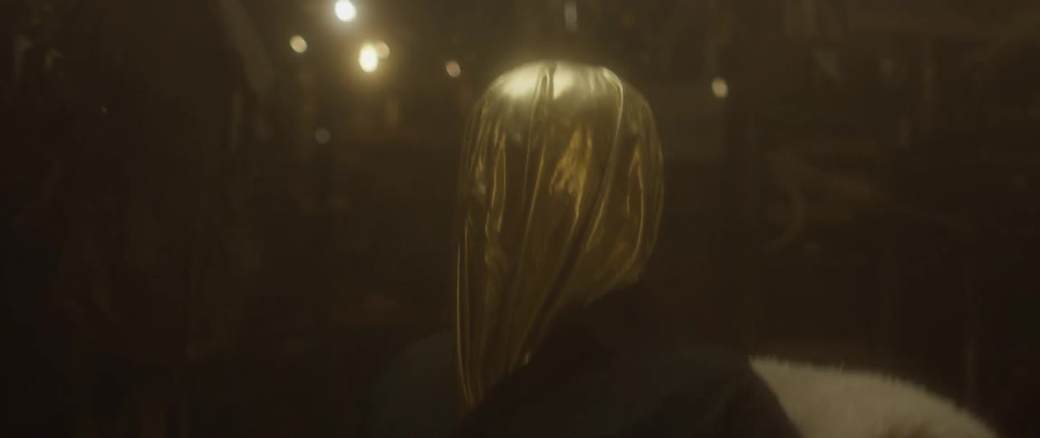 A man is sitting wearing a golden hood