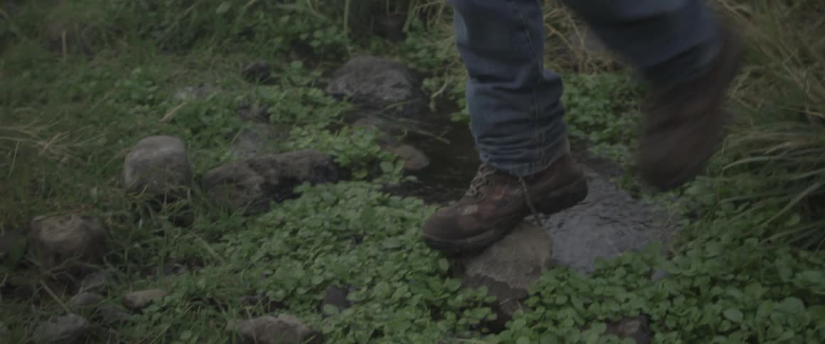 A person walks over a small puddle on a rock