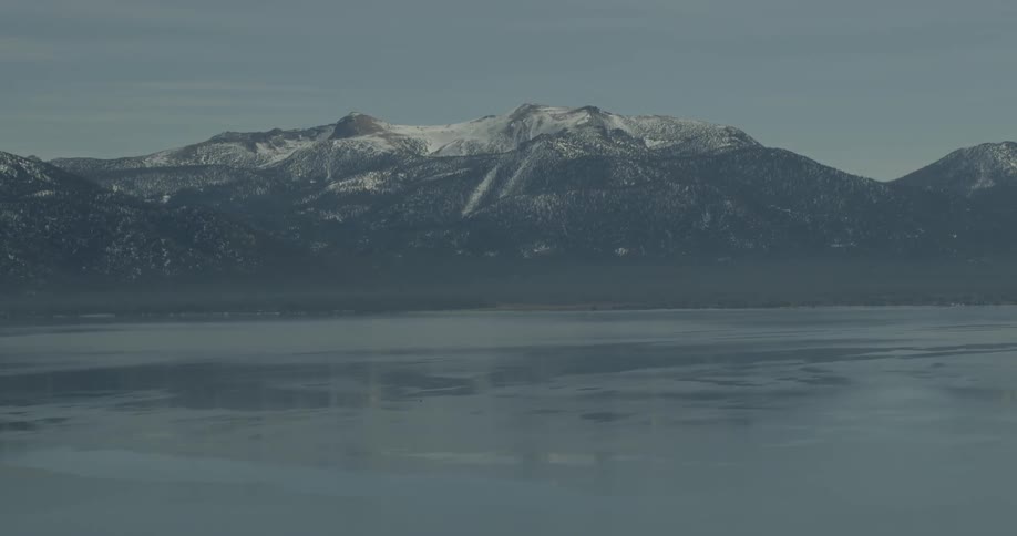 A snow capped mountain is reflected in a body of water in Lake Tahoe, California