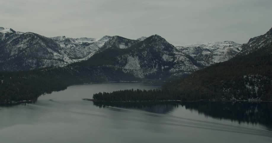 A boat travels around the mountain in the water in Lake Tahoe, California