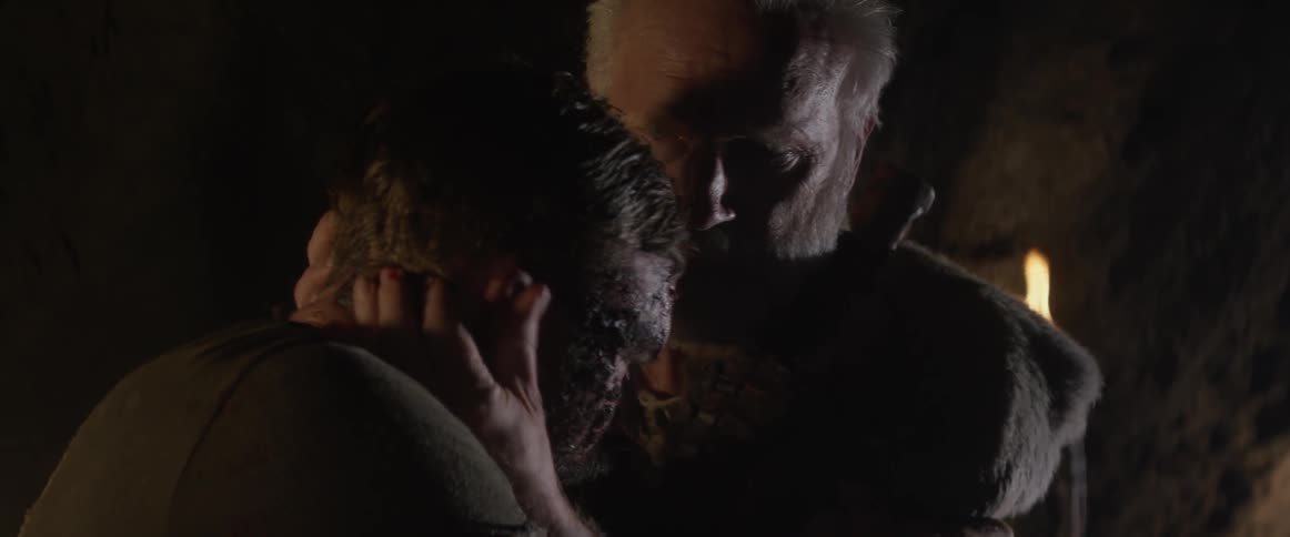 An elderly man hugs a man with an injured and bleeding face
