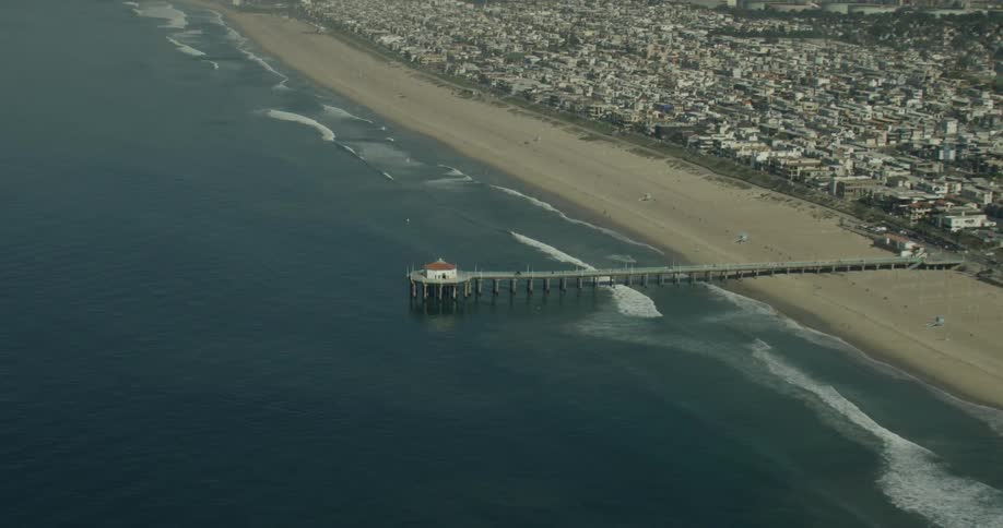 Waves flow onto the sand on the shoreline near a pier off the coast of California